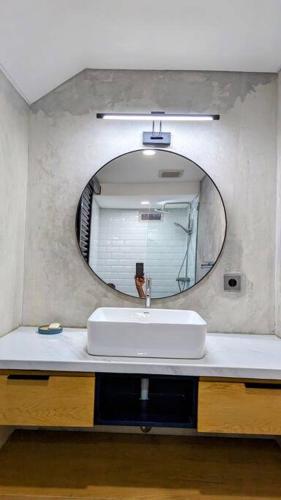 ein Waschbecken mit einem runden Spiegel darüber in der Unterkunft Beji Loft in Dalung