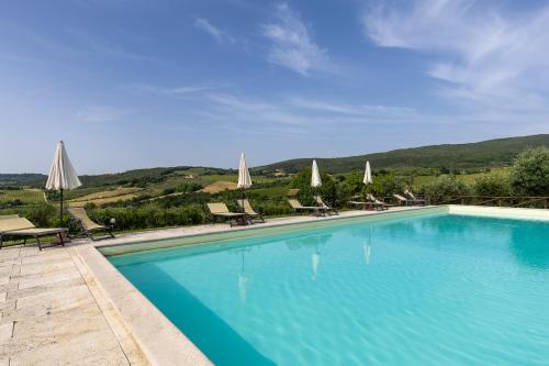 a large blue swimming pool with chairs and umbrellas at Suite Fattoressa in San Gimignano