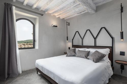 a bedroom with a large white bed and a window at Suite Fattoressa in San Gimignano