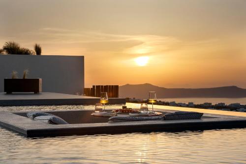 a pool with a sunset in the background at North Santorini - A Luxury Spa Hotel in Pirgos