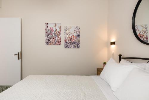 a bedroom with a white bed with two paintings on the wall at ALS Holiday Houses by Konnect, 900m from Ipsos Beach in Ýpsos