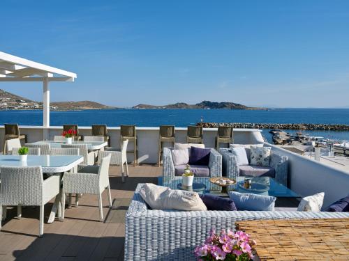 um pátio com mesas e cadeiras e o oceano em Hotel Galini em Naousa