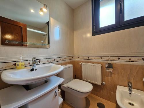 a bathroom with a sink and a toilet and a mirror at El Mirador de Llaneces 24A02 in Arenas de Cabrales