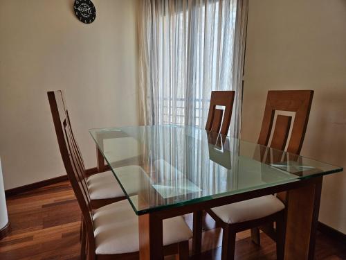 a dining room table with four chairs and a glass top at El Mirador de Llaneces 24A02 in Arenas de Cabrales