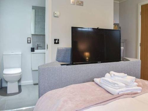 1 dormitorio con TV y 1 cama con toallas en Gorstage Meadows Luxury 2 Bedroom Lodge in Rural Cheshire en Hartford