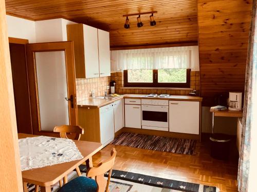 een keuken met witte kasten, een tafel en een wastafel bij Appartements D'Angelo in Bodensdorf