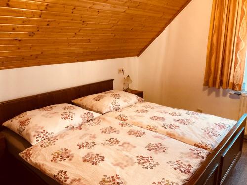 a bed in a bedroom with a wooden ceiling at Appartements D'Angelo in Bodensdorf