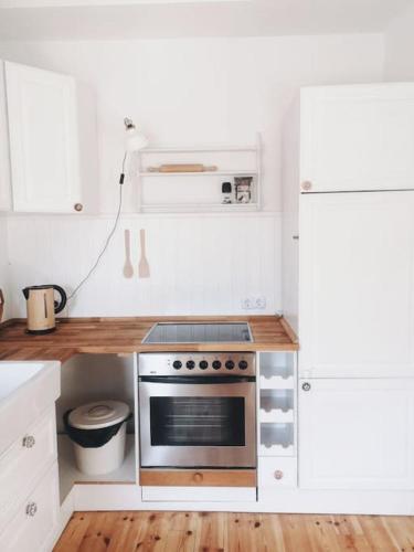a kitchen with white cabinets and a stove top oven at Urlaub auf einem alten Resthof am Meer in Gelting