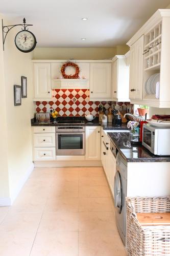 a kitchen with white cabinets and a tile floor at Glandore mews situated in the picturesque village of Glandore in Glandore