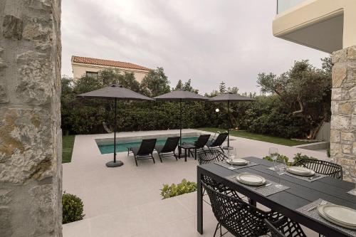 a patio with a table and chairs and umbrellas at Villa Nineta in Tavronitis