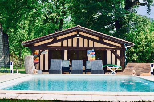 - un kiosque avec des chaises et une table à côté de la piscine dans l'établissement Les gîtes du petit mila, à Labrit