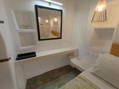 um quarto branco com um espelho e uma cama em Sea Melody Tinos em Ayios Sostis