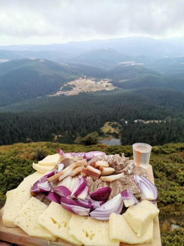 a plate of cheese and onions on top of a mountain at Izvorul Prigoanei in Tău Bistra
