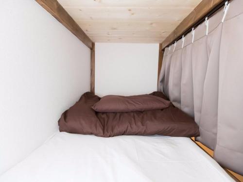 a small bed in a small room with white walls at Osaka Namba Hostel MIYABI in Osaka