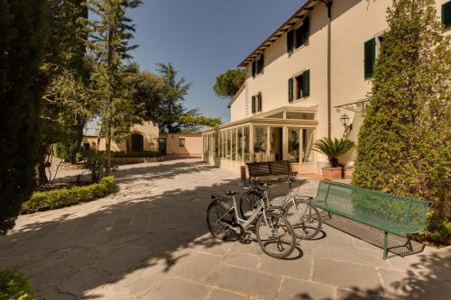 a bike parked next to a bench next to a building at Villa I Barronci Resort & Spa in San Casciano in Val di Pesa