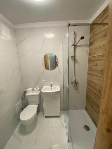 a white bathroom with a toilet and a shower at Kryształowa Przystań in Mrzeżyno