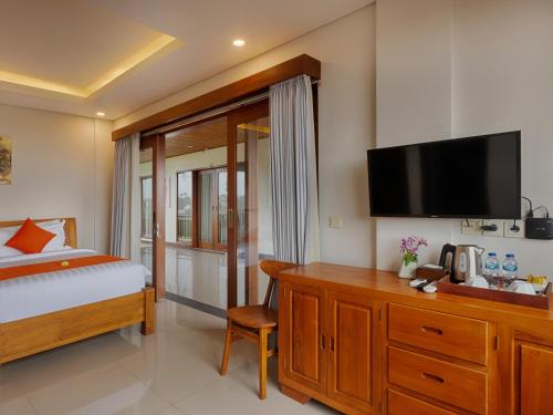a bedroom with a bed and a desk with a television at Kubu Belona Canggu in Canggu