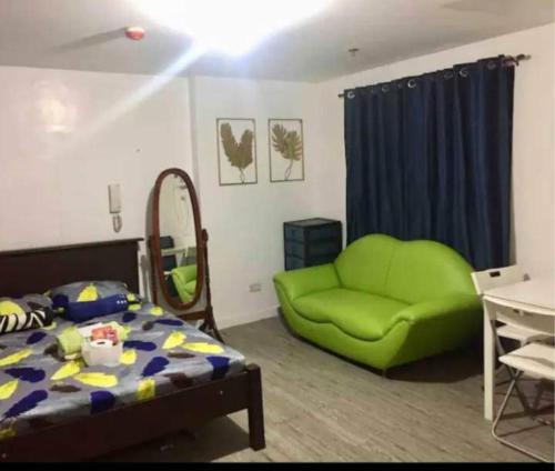 1 dormitorio con 1 cama y 1 sofá verde en ADB Avenue Tower Ortigas Manila, en Manila