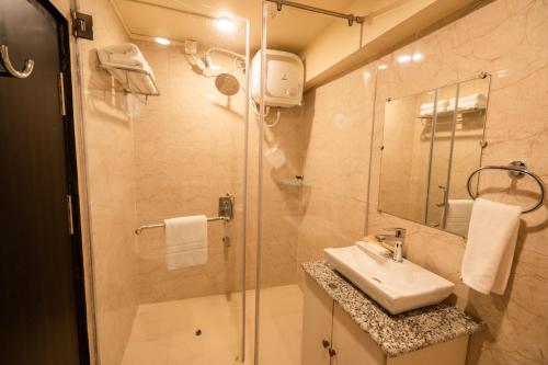 ein Bad mit einer Dusche, einem Waschbecken und einem Spiegel in der Unterkunft ROYALE LALAWI HOTEL in Aizawl