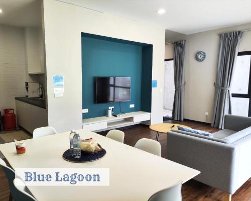 Roxy Sematan Townhouse - Blue Lagoon في Sematan: غرفة معيشة مع طاولة بيضاء وغرفة زرقاء