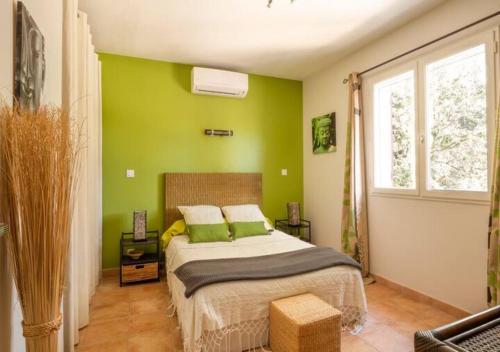 Les Jardins d'Holi proche Uzès في Garrigues-et-Sainte-Eulalie: غرفة نوم بجدران خضراء وسرير بمخدات خضراء