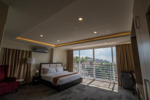 um quarto de hotel com uma cama e uma grande janela em ROYALE LALAWI HOTEL em Āīzawl