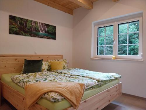 a bedroom with a bed and two windows at Ferienhaus Fellbacher, Weißensee in Stockenboi