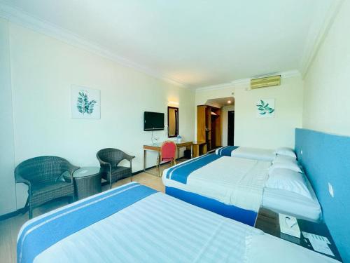 una camera d'albergo con due letti e una televisione di Tyng Garden Hotel a Sandakan
