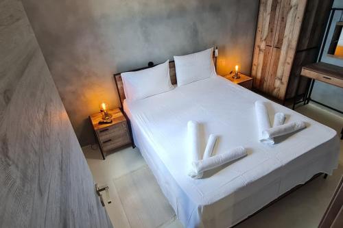 a bedroom with a large white bed with two candles at ManiTu in Éxo Nímfion