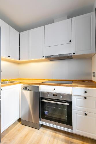 a kitchen with white cabinets and a stainless steel oven at H-A Aparthotel Hotel Quo in Madrid