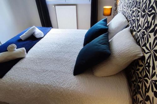 a bed with blue and white pillows on it at Calme - Bien équipé - Parking -Terrasse in Pau