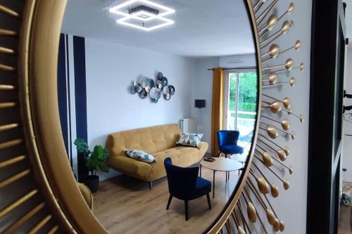a mirror reflecting a living room with a couch and a table at Calme - Bien équipé - Parking -Terrasse in Pau