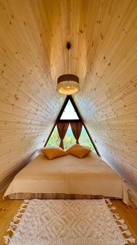 a bed in a wooden room with a window at Magical space Tsikhisdziri in Ts'ikhisdziri