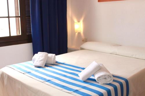 a hotel room with a bed with towels on it at Apartamentos Posidonia in Son Parc