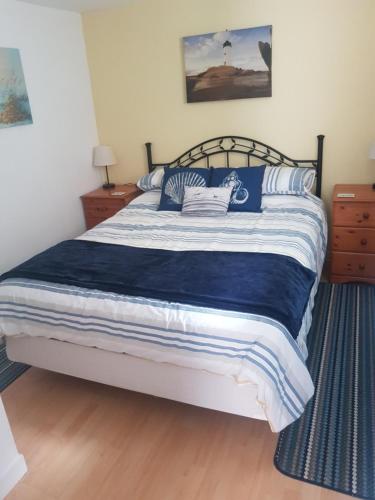 a bedroom with a large bed with blue and white sheets at 1 Taits Flat in Orkney