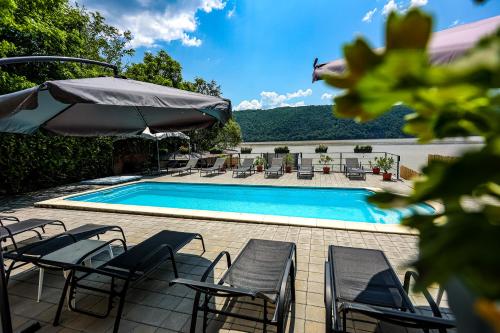 einen Pool mit Stühlen und einem Sonnenschirm in der Unterkunft Casa Celestin in Eşelniţa