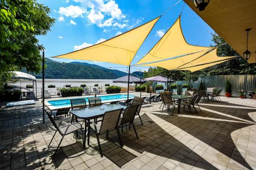 a patio with tables and chairs and a pool at Pensiunea Celestin in Eşelniţa