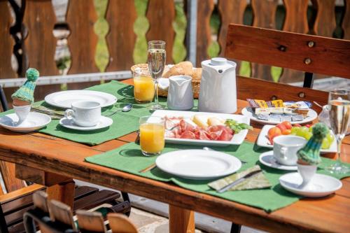 a wooden table with a plate of food and orange juice at MOUNTAIN RESIDENCE ALPENHOF - company Hotel Alpenhof KG sas der Gasser Renate in Bressanone