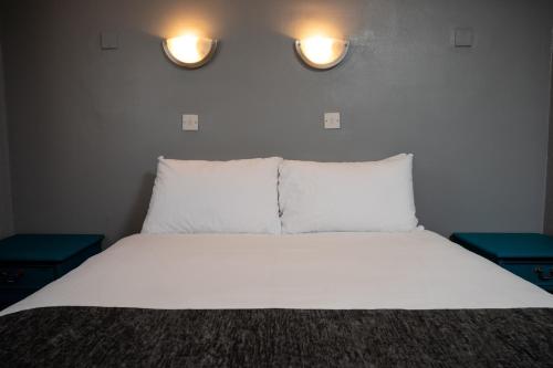 a bedroom with a bed with two lights on the wall at The Longship in Hebburn-on-Tyne