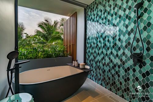 a bathroom with a bath tub and a glass wall at Sailing Club Signature Resort Phu Quoc in Phu Quoc