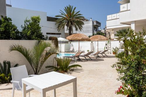 d'une terrasse avec des chaises, une table blanche et un parasol. dans l'établissement La Gemma del Salento, à Racale