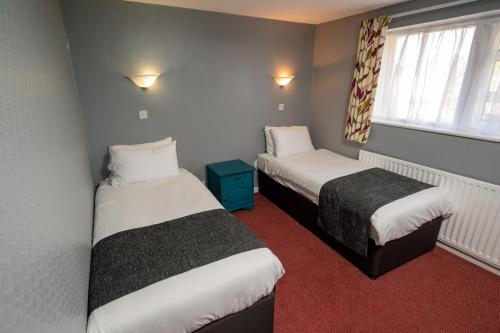 a hotel room with two beds and a window at The Longship in Hebburn-on-Tyne