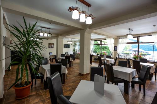 a restaurant with tables and chairs and a plant at Pensiunea Celestin in Eşelniţa