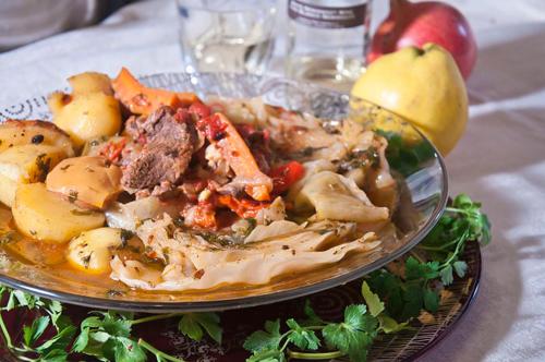 um prato de alimentos com carne e legumes sobre uma mesa em Taj Altyn Hotel em Kaji-Say