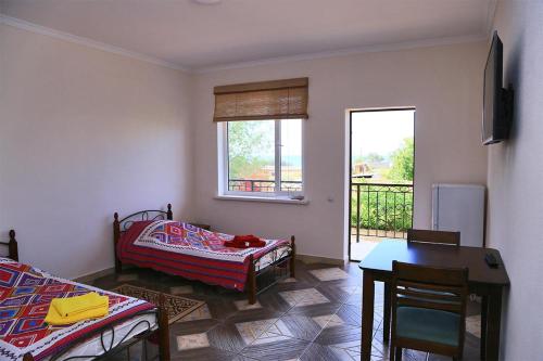 a living room with a table and a bed and a window at Taj Altyn Hotel in Kaji-Say