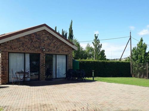 a brick house with a patio with a table and chairs at de Klerens Gems : Emerald Self Catering Unit in Clarens