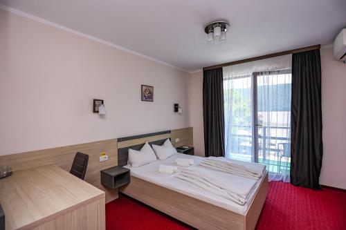 Schlafzimmer mit einem Bett, einem Schreibtisch und einem Fenster in der Unterkunft Casa Celestin in Eşelniţa
