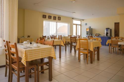 um restaurante com mesas e cadeiras com toalha de mesa amarela e branca em Imperio Hotel em Peso da Régua