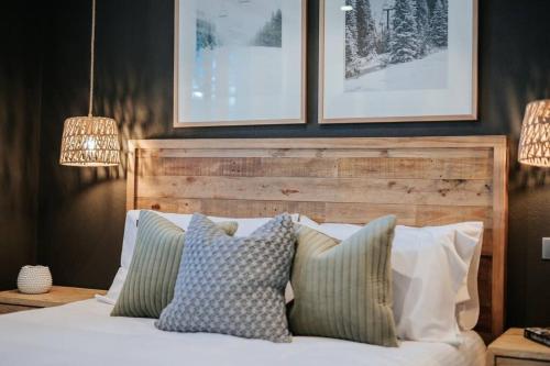 1 dormitorio con 1 cama con almohadas y cuadros en la pared en Luxury Alpine Apartment in the Centre Of It All en Mount Hotham