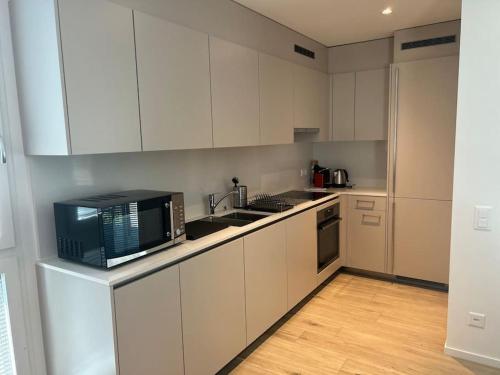 een keuken met witte kasten en een zwarte magnetron bij LabPark Modern apartment in Melano